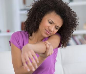 Woman holding her elbow with a pained expression on her face