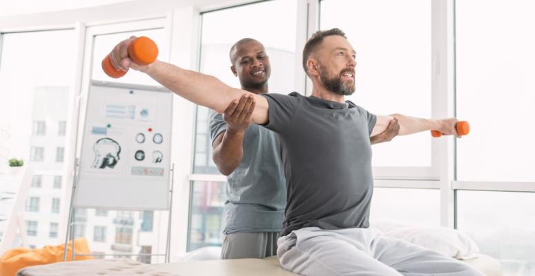 Physical therapist helping patient lift weights