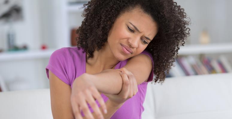 Woman holding her elbow with a pained expression on her face